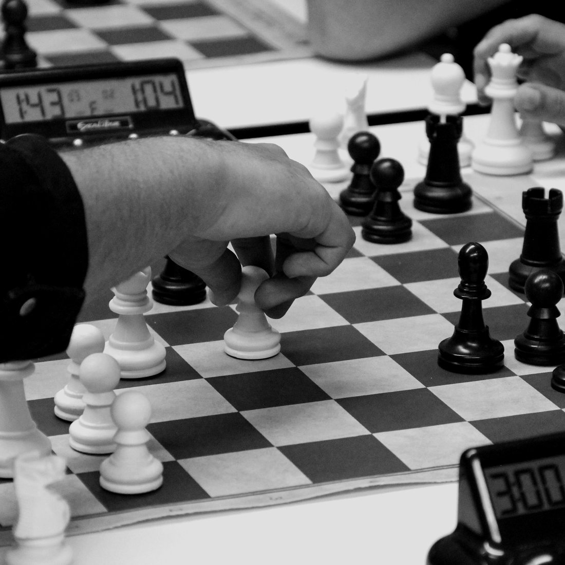 Two players' hands over a chessboard, with the chess clocks running